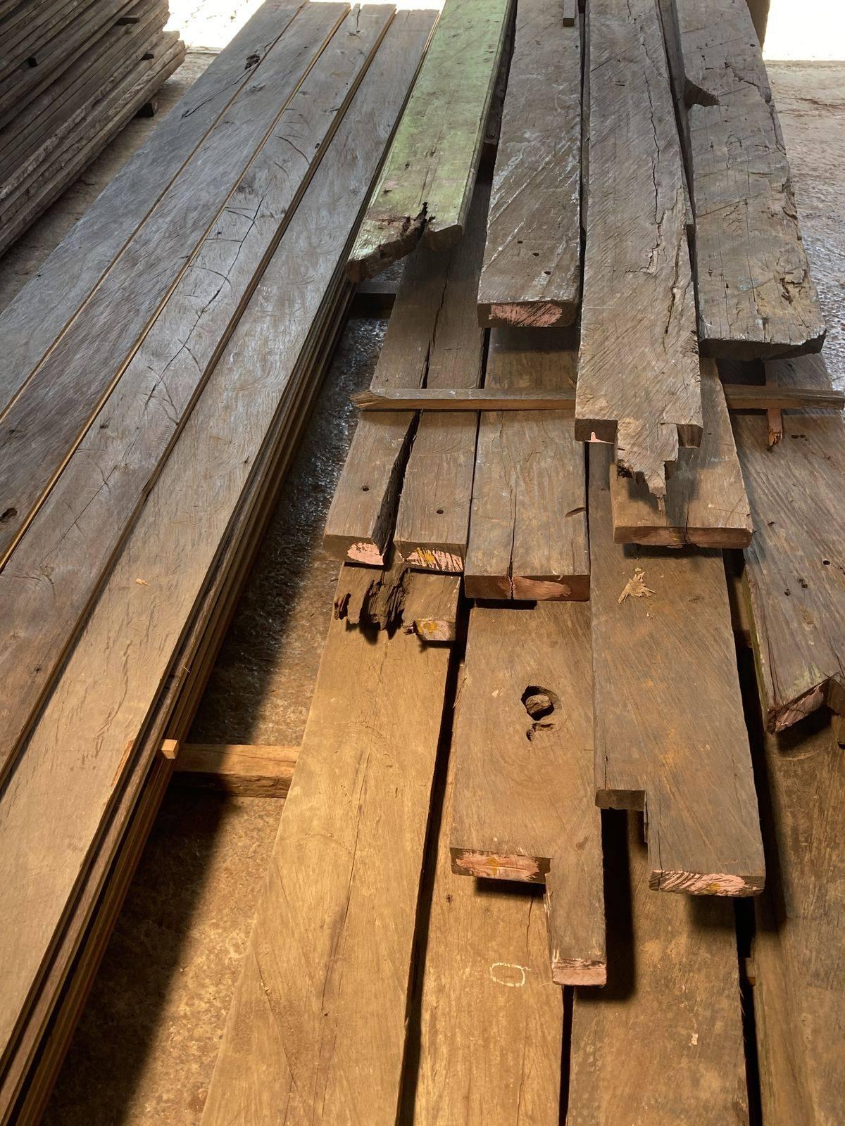 Reclaimed belian planks stacked on a concrete floor, silver-grey where they have weathered for decades and orange-brown where they have been freshly cut